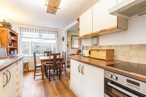 Una cucina moderna con mobili in legno, un tavolo da pranzo con sedie e un forno integrato.