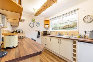 A modern kitchen with wooden countertops, a built-in microwave, and a window with a view of the outdoors. - Host & Stay | Wylaway (Norwich)