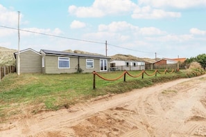 A single-story mobile home with a fenced yard, a dirt path, and a grassy area. - Host & Stay | Wylaway (Norwich)