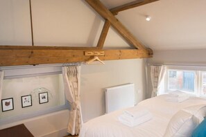 A bedroom with a bed, a radiator, and a window with curtains.