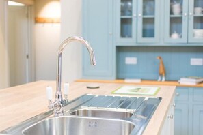 Een keuken met een roestvrijstalen spoelbak, een kraan en een houten aanrecht.