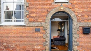 A brick building with a stone archway entrance leading to a room with a sofa and a lamp. - Host & Stay | The Chapel in Thornham (Thornham)