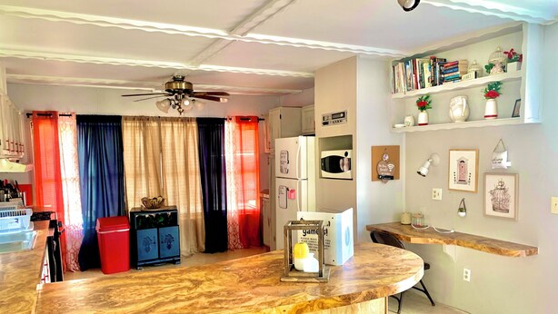 A modern kitchen with a wooden island, bar stools, a ceiling fan, and a refrigerator. - A home away from home!  (Hydro)
