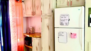 A compact kitchen with white cabinets, a white refrigerator, and a ceiling fan. - A home away from home!  (Hydro)