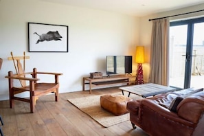 A room with a wooden chair, a sofa, a small table, a lamp, and a framed picture on the wall.