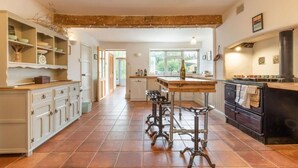 A spacious kitchen with a central island, white cabinetry, and a large window providing natural light. - Host & Stay | Mill House (Worthing)