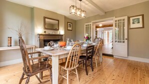 A dining area with a wooden table and chairs, a chandelier, and a fireplace. - Host & Stay | Mill House (Worthing)