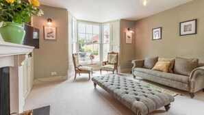 A cozy living room with a fireplace, a sofa, an ottoman, and a dining area with chairs. - Host & Stay | Mill House (Worthing)