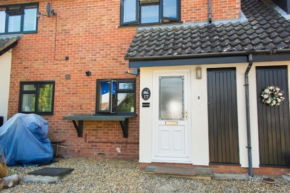 A brick house with a white door, a black doorbell, and a small porch.