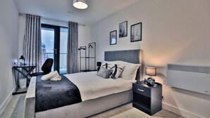 Et moderne hotelværelse med en stor seng, sengeborde, et skrivebord og udsigt over byen.