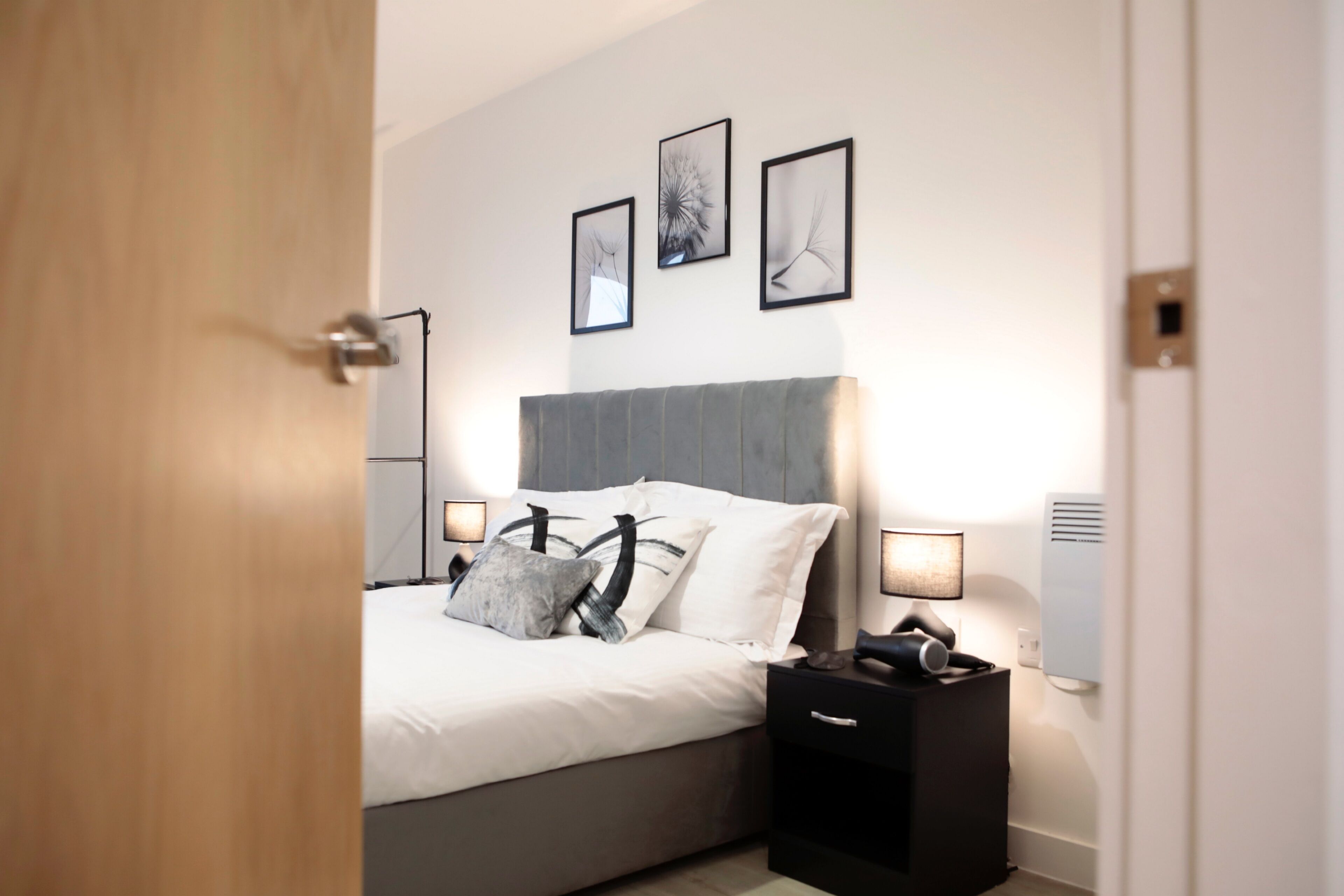 A modern bedroom with a bed, bedside tables, and wall-mounted artwork.