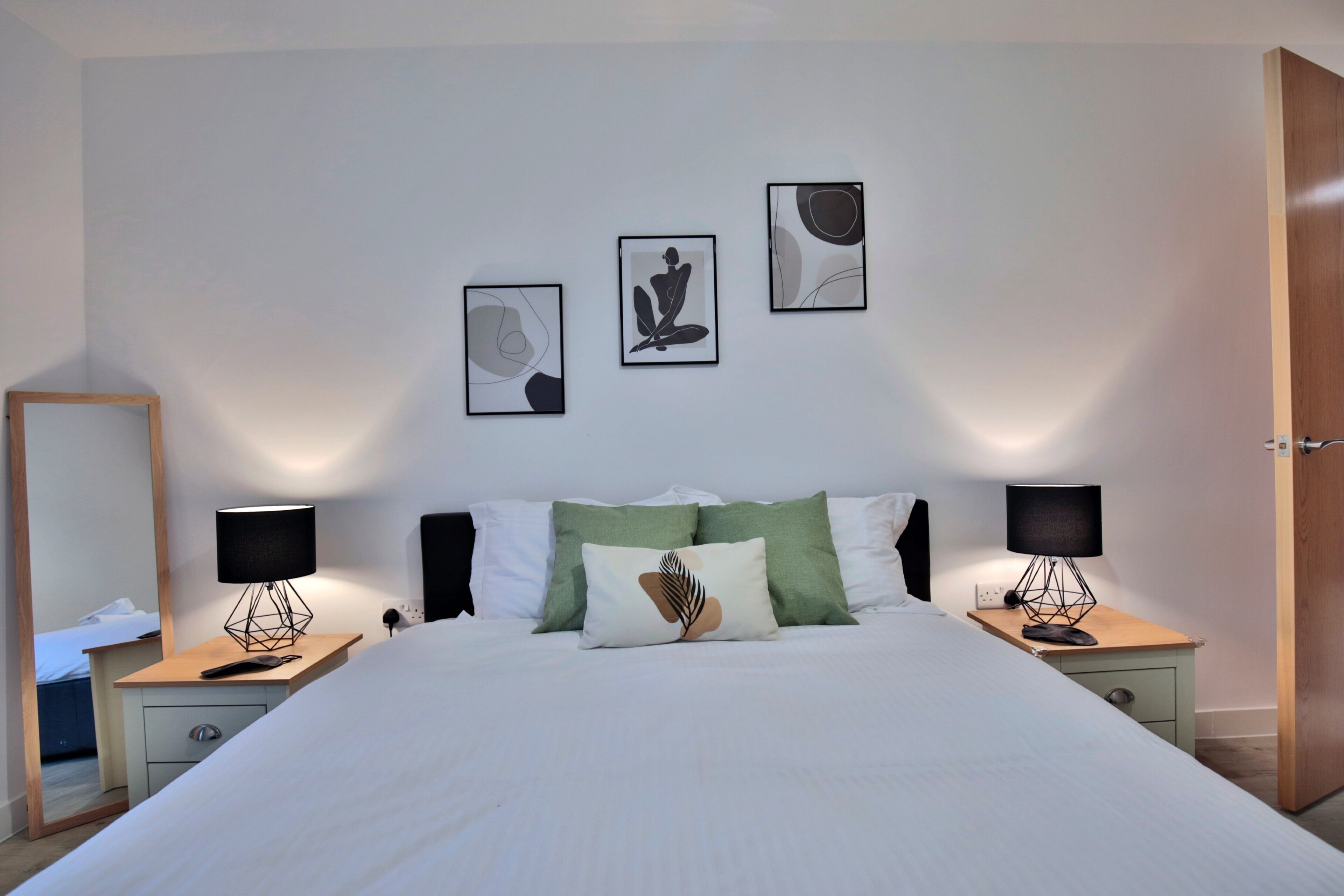A neatly arranged bedroom with a large bed, two bedside tables, and three wall-mounted artworks.