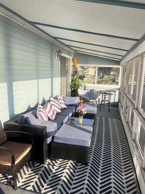 A covered outdoor seating area with a sofa, chairs, and a table. - Sublime Sunsets--Charming Cottage with No Bad Views (King Ferry)