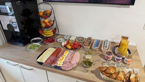 Een buffet met diverse soorten eten, zoals fruit, kazen, vleeswaren en sauzen.