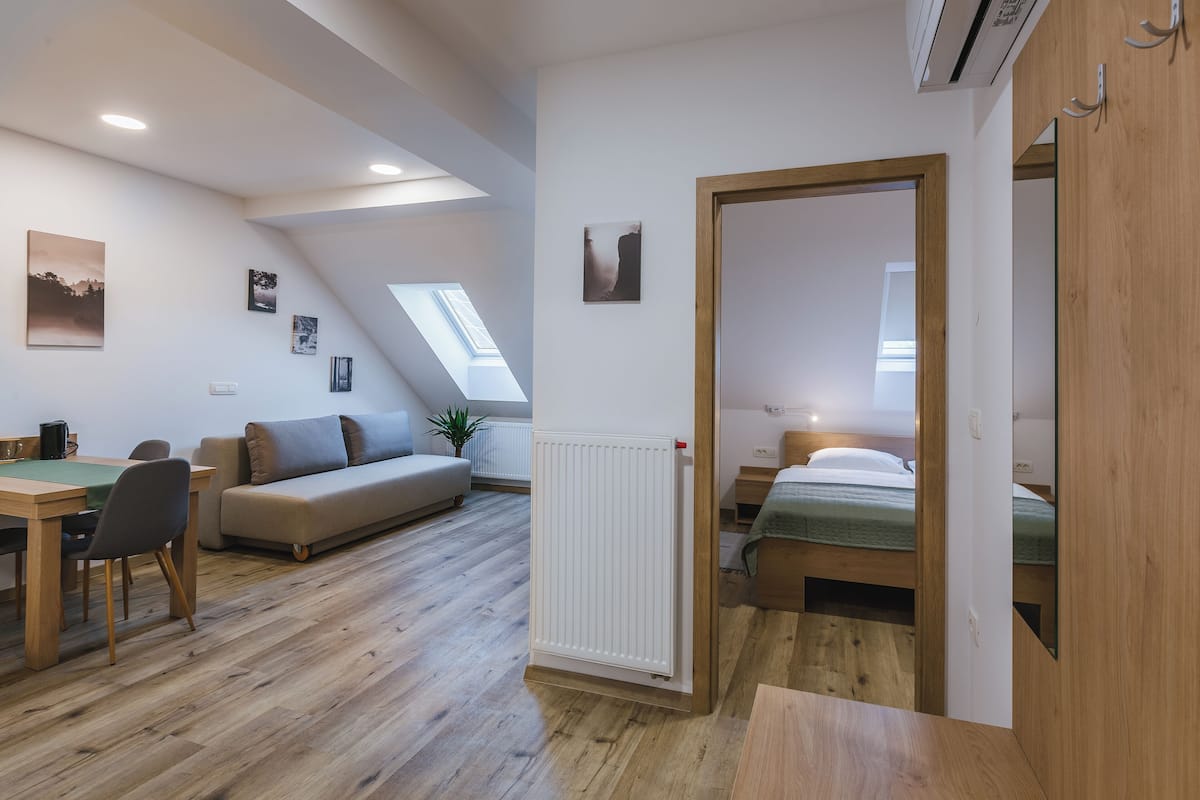 Een moderne, goed verlichte kamer met een eethoek, een bank, een bed en een dakraam.