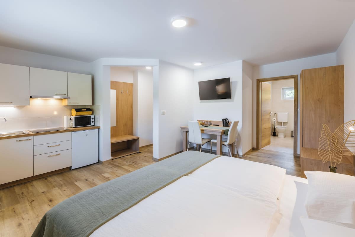 Een kleine hotelkamer met een bed, kitchenette en bureau.