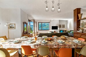 Un coin repas avec une table dressée pour quatre personnes, un canapé et un téléviseur en arrière-plan.