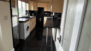 A modern kitchen with black countertops, a built-in washing machine, and a large window providing natural light. - Durham, 3-beds, Sleeps 5 - Close to Uni & Centre (Durham)