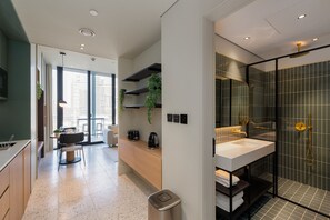 A modern kitchen with a built-in oven, a dining area with a table and chairs, and a large window providing natural light. - Cozy Studio w/ Burj View Balcony, Business Bay (Dubai)