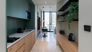 A modern kitchen with a central island, built-in appliances, and a view to the living area. - Cozy Studio w/ Burj View Balcony, Business Bay (Dubai)