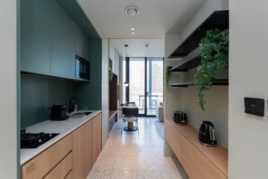A modern kitchen with a central island, built-in appliances, and a view to the living area. - Cozy Studio w/ Burj View Balcony, Business Bay (Dubai)