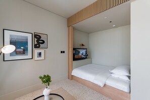 A modern bedroom with a bed, a TV mounted on the wall, and framed artwork on the wall.