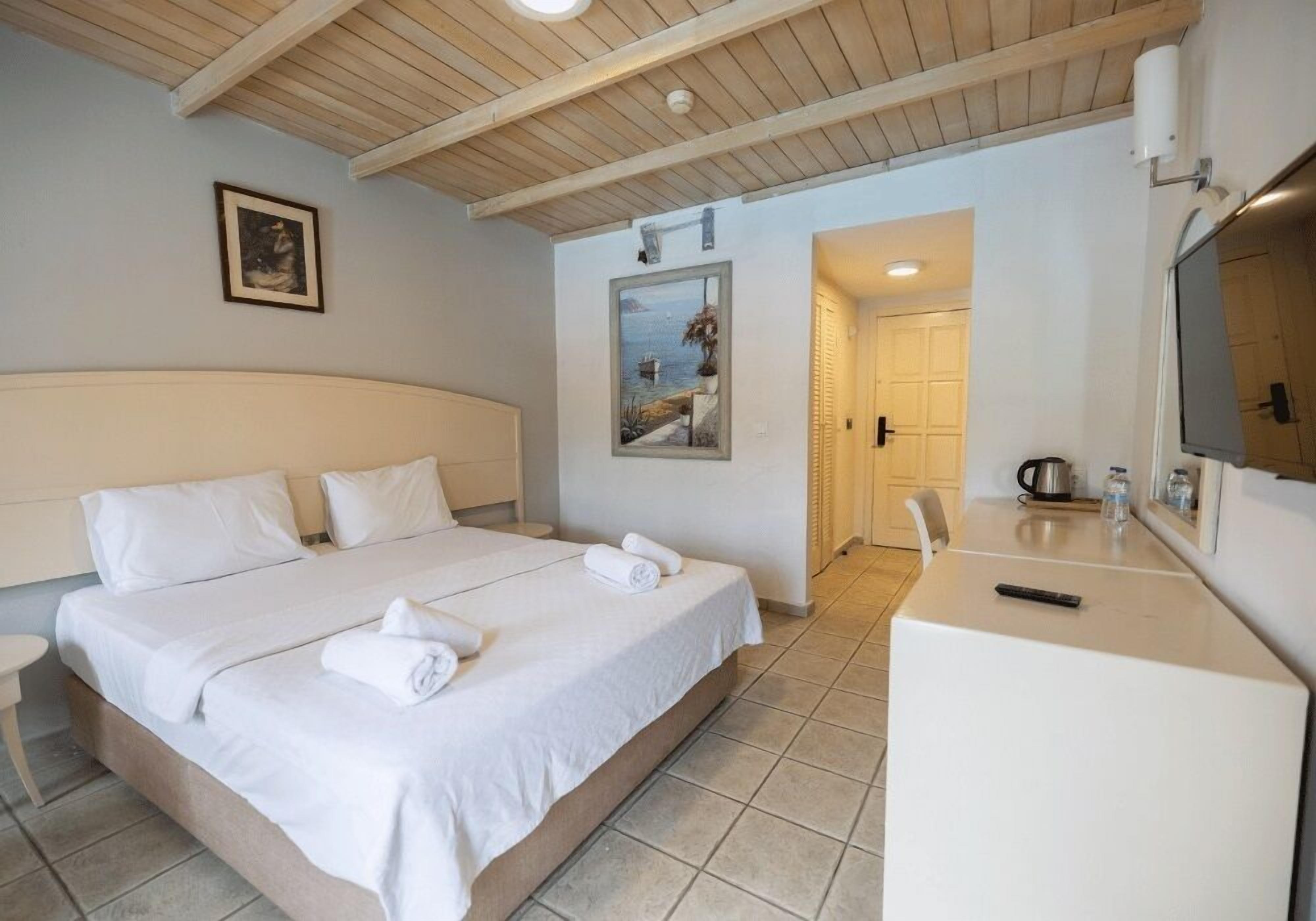 A hotel room with a bed, a desk, a bathroom, and a view of the sea.