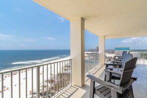 Un balcon avec vue sur la plage et l’océan. On y trouve des chaises et une table.