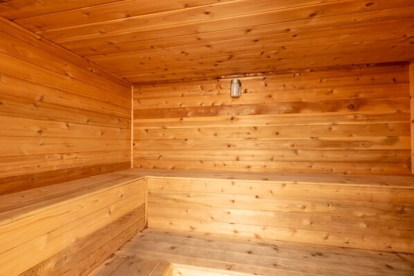 Un sauna en bois, doté de bancs et d’un radiateur fixé au mur.