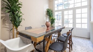 A dining area with a glass table, wooden chairs, and potted plants. - Vintage Acropolis Retreat: Charming 3-Bdrm in Koukaki (Athens)