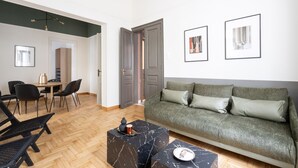 A modern living room with a green sofa, black coffee table, and a dining area with a table and chairs. - Vintage Acropolis Retreat: Charming 3-Bdrm in Koukaki (Athens)