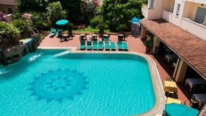 A swimming pool with a circular pattern in the center, surrounded by lounge chairs and umbrellas. - Apartments In Golfo Orosei (Orosei)