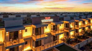 A multi-story hotel with a rooftop pool and a sign reading 'Wariruri.'