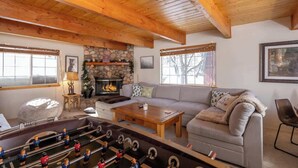 A cozy living room with a fireplace, a sofa, a coffee table, and a foosball table.