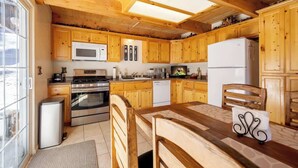 A wooden kitchen with a stove, microwave, and refrigerator.