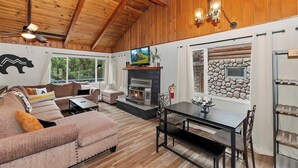 Una sala de estar acogedora con chimenea, techo de madera y pared de piedra.