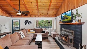 Una sala de estar acogedora con chimenea, techo de madera y televisor.