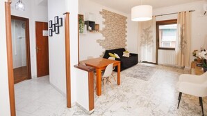 A modern living room with a marble floor, a black sofa, a wooden dining table, and a white armchair. - Rhome Suite Vatican APTS (ROMA)