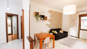 A modern living room with a dining table, a black sofa, and a stone accent wall. - Rhome Suite Vatican APTS (ROMA)