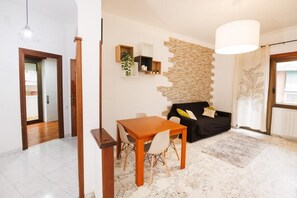 Relax in this stylish living space with a dining area, sofa, and large window offering a view of the outdoors.