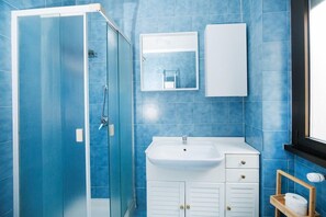 Bathroom features a glass-enclosed shower, sink with single faucet, and mirror.