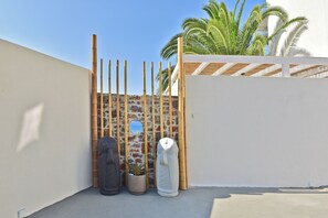 Un espace clos délimité par un mur de pierre, une clôture en bambou et un pot de fleurs.