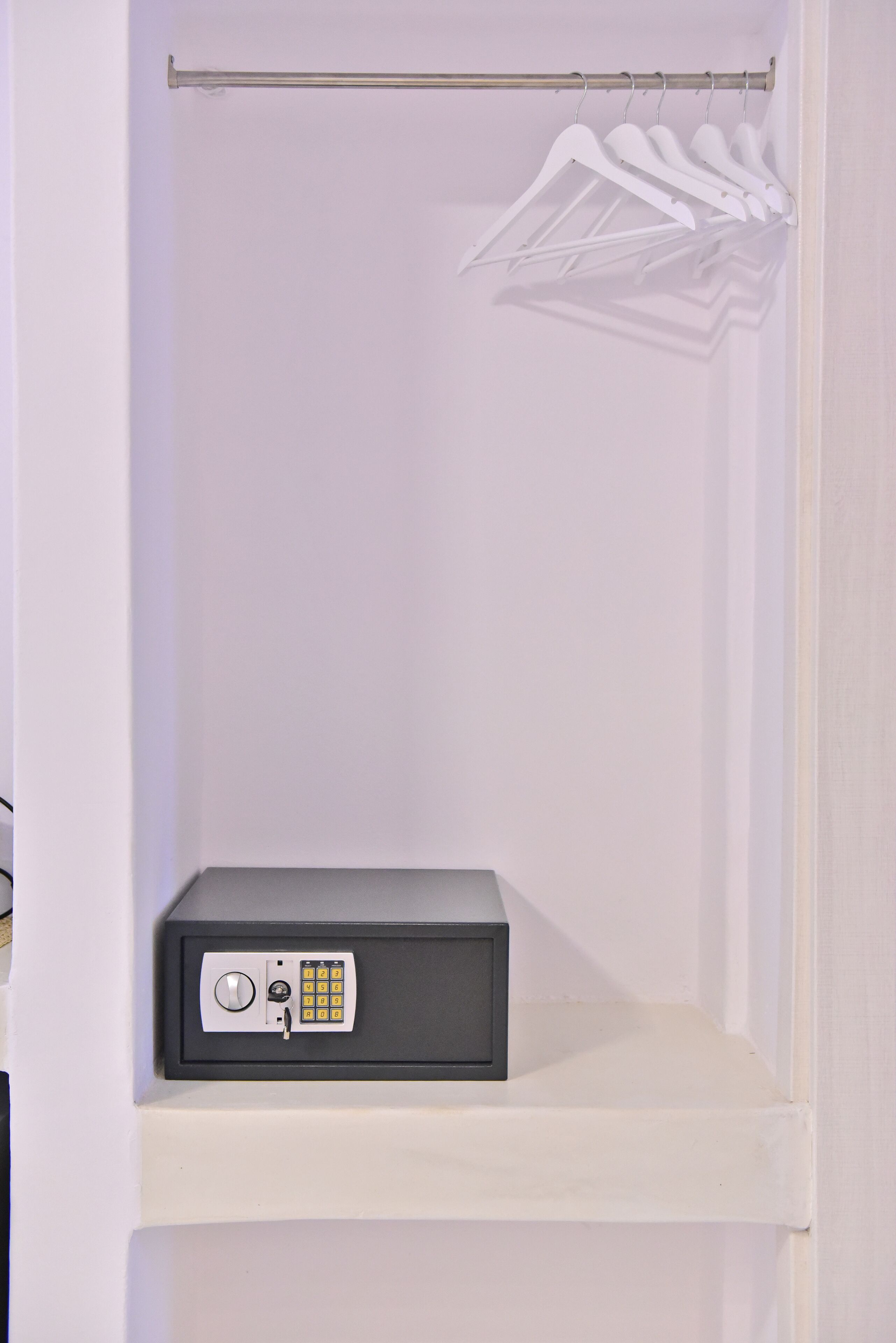 A white closet with a grey storage unit and a hanging rod with white hangers.