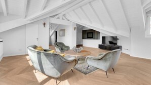 A spacious loft with high ceilings, a central round table, and modern furniture.