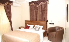 Une chambre d’hôtel avec un lit, une chaise et des rideaux.