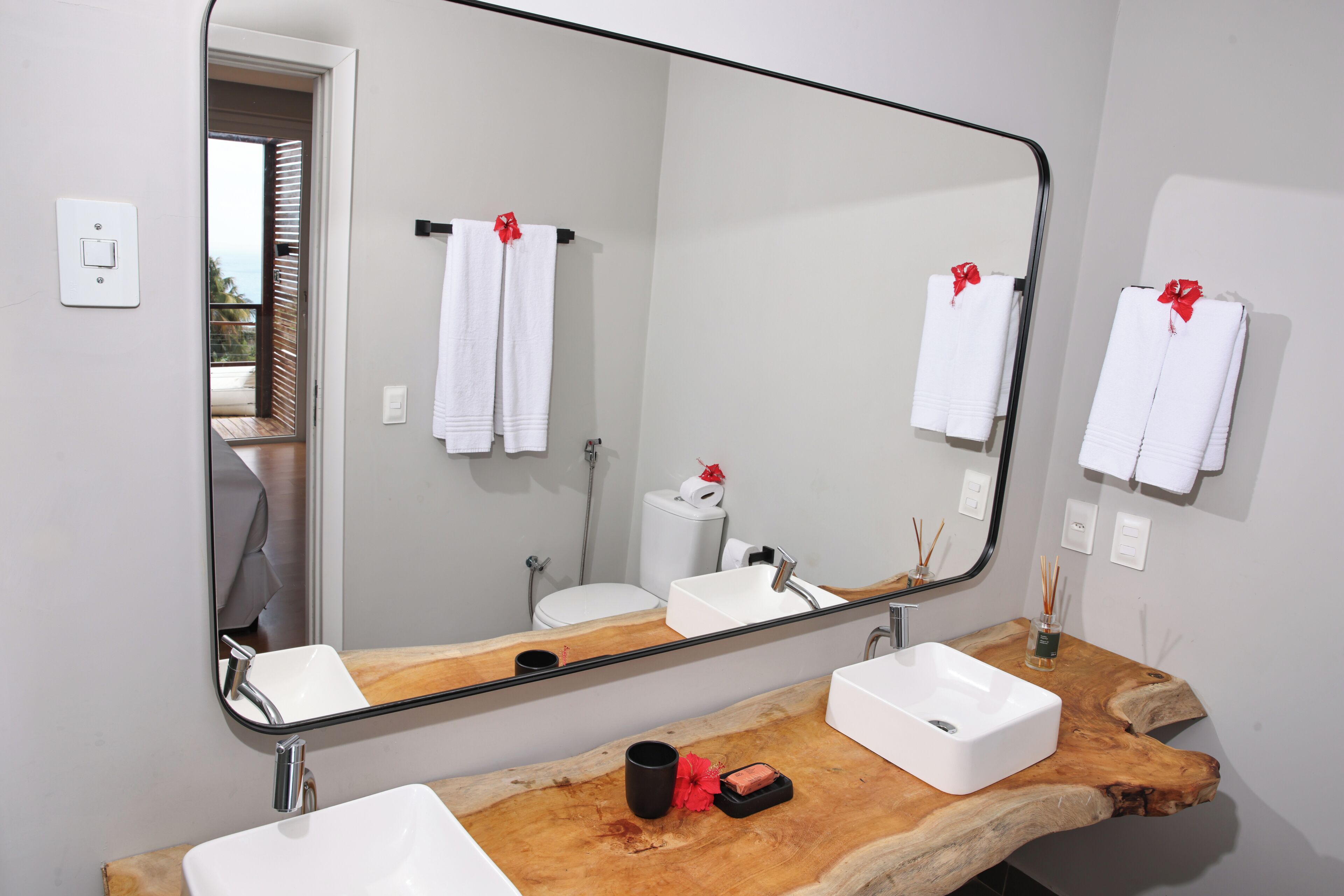A bathroom with a wooden vanity, two sinks, a large mirror, and towels with red bows.