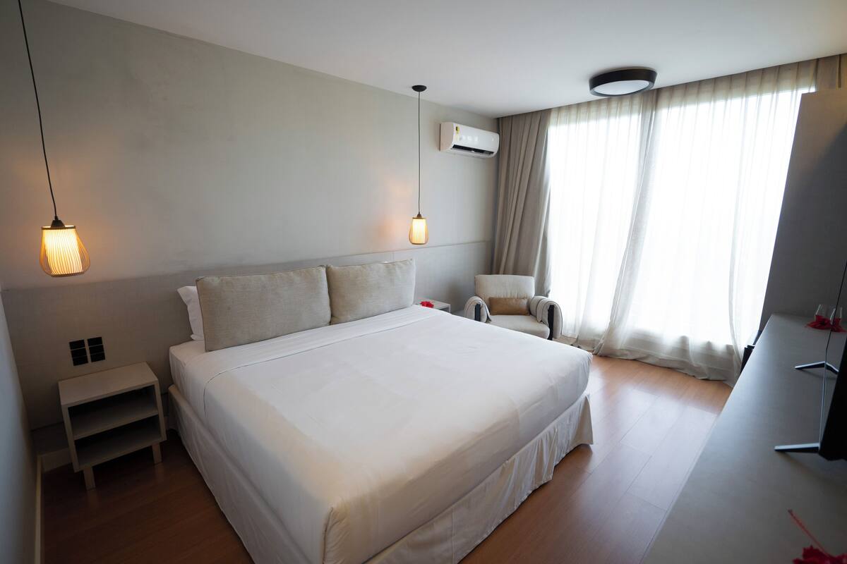 A modern hotel room with a large bed, bedside tables, a desk, and a chair.