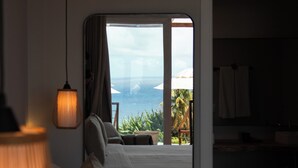 Une chambre d’hôtel avec un lit, une lampe suspendue et une vue sur l’océan.