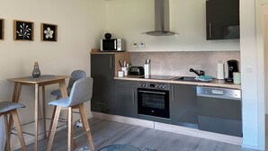 Eine moderne Küche mit Mikrowelle, Toaster, Backofen und Geschirrspüler. Es gibt einen Essbereich mit Tisch und Stühlen.