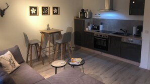 Ein kompakter Wohnraum mit Küchenzeile, einer Essecke mit Tisch und Stühlen sowie einer Sitzecke mit Sofa.